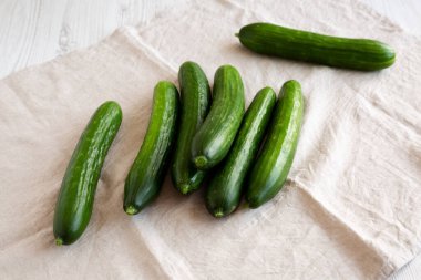 Beyaz ahşap arka planda organik Mini Bebek Salatalıkları, yan görüş.