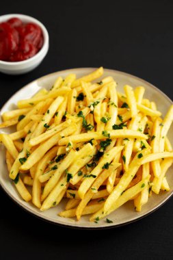 Siyah arka planda maydanozlu sarımsaklı patates kızartması. Yakın plan..