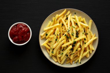 Siyah arka planda maydanozlu sarımsaklı patates kızartması. Yukarıdan, dümdüz uzanmış.