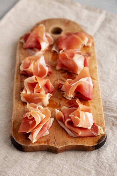 Slices of Appetizing Jamon Serrano Ready to Eat on a rustic wooden board, side view. 