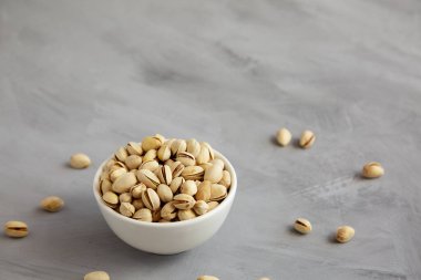 Tuzlu ve kavrulmuş Pistachio 'lar gri arka planda, yan manzaralı bir kasede. Metin için boşluk.