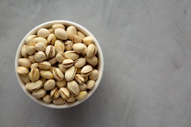 Tuzlu ve kavrulmuş Pistachio 'lar gri arka planda, üst tarafta. Yukarıdan, dümdüz yatıyordu. Boşluğu kopyala.