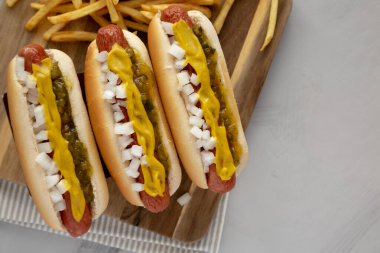 Hardallı, soğanlı ve turşulu ev yapımı sosisli sandviçler ahşap bir tahtanın üstünde. Boşluğu kopyala.