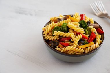 Ev yapımı sarımsaklı sebzeli makarna, gri arka planda, yan manzaralı. Boşluğu kopyala.