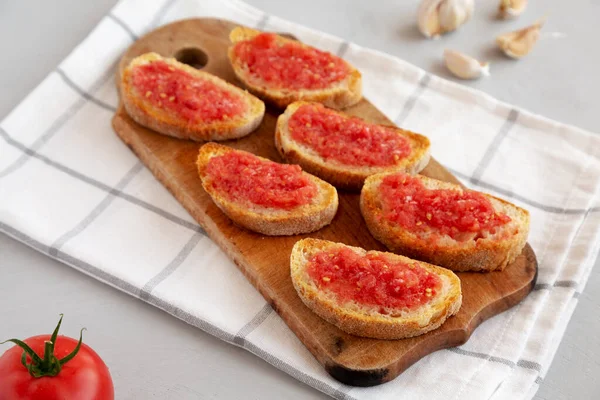 Homemade Pan Con Tomate (Tomato Toast) on a Rustic Wooden Board, side view.