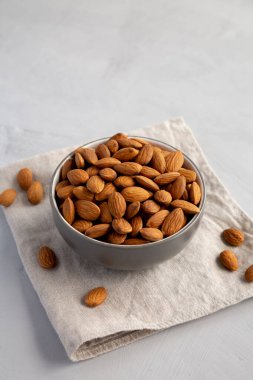 Gri arka planda, bir kasede çiğ organik badem.. 