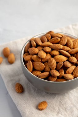 Gri arka planda, bir kasede çiğ organik badem.. 