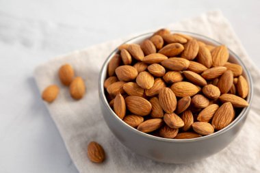 Gri arka planda, bir kasede çiğ organik badem.. 