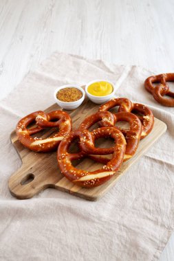 Tahta üzerinde hardal olan ev yapımı yumuşak Bavyera krakerleri.. 