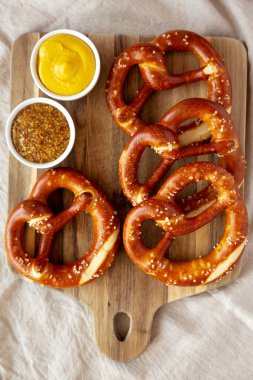 Tahta üzerinde hardal olan ev yapımı yumuşak Bavyera krakerleri..