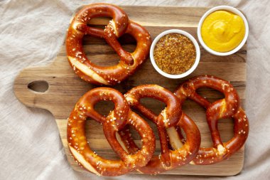 Tahta üzerinde hardal olan ev yapımı yumuşak Bavyera krakerleri..