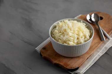 Ev yapımı Alman lahana turşusu gri arka planda, yan manzaralı bir kasede. Boşluğu kopyala.