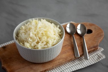 Ev yapımı Alman lahana turşusu gri arka planda, yan manzaralı bir kasede..