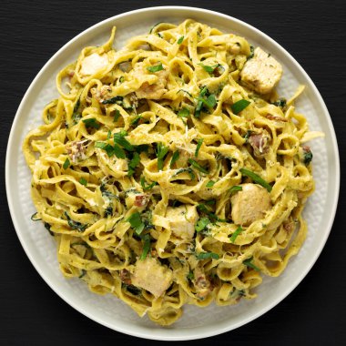 Siyah arka planda, tabakta ev yapımı kremalı tavuk pastırmalı makarna. Dümdüz, tepeden, yukarıdan. 