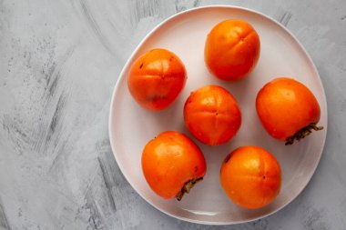 Gri arka planda, plaka üzerinde organik hurma ağacı meyvesi, üst manzara. Dümdüz, tepeden, yukarıdan. Boşluğu kopyala.