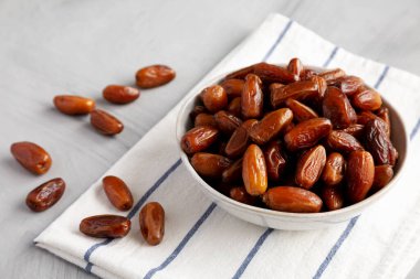 Bir kasedeki organik çiğ tarih meyvesi, yan görünüm.