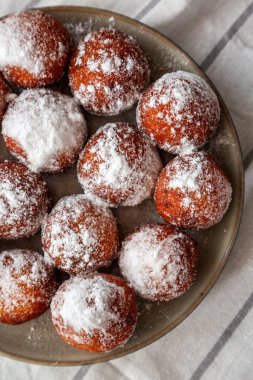 Tabakta toz şekerli ev yapımı kızarmış donut delikleri, genel görünüm.