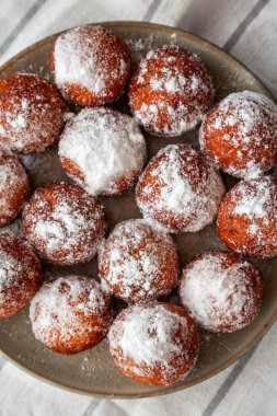 Tabakta toz şekerli ev yapımı kızarmış donut delikleri, genel görünüm.
