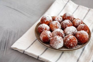 Tabakta pudra şekerli ev yapımı kızarmış çörek delikleri, yan manzara. Boşluğu kopyala.