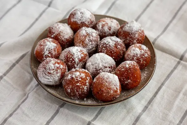 Tabakta pudra şekerli ev yapımı kızarmış çörek delikleri, yan manzara..