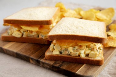 Tahta tahtada patates cipsli ev yapımı yumurta salatalı sandviç. Yakın plan..