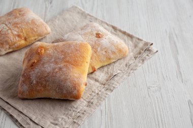 Beyaz ahşap arka planda ev yapımı Cheese Ciabatta çörekleri, yan manzara. Boşluğu kopyala.