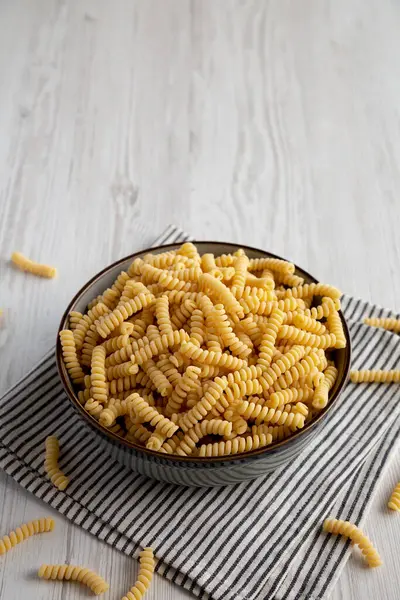 stock image Raw Dry Organic Italian Fusilli Corti Bucati in a Bowl, side view. Copy space.