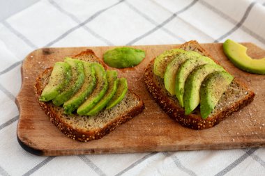 Ev yapımı Avokado tostu, ahşap tahtada tuz ve biberli, yan manzaralı..