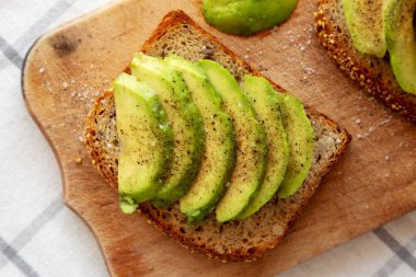 Ev yapımı Avokado tostu, ahşap bir tahtanın üzerinde tuz ve biberli, üst manzara..