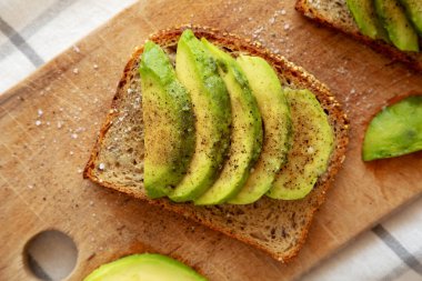 Ev yapımı Avokado tostu, ahşap bir tahtanın üzerinde tuz ve biberli, üst manzara..