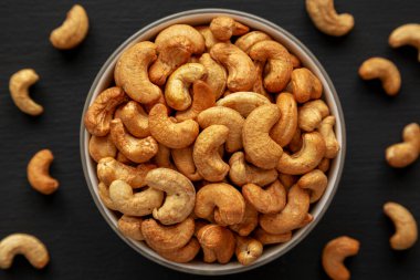 Siyah arka planda, bir kasede kızarmış organik kaju, üst görünümde..