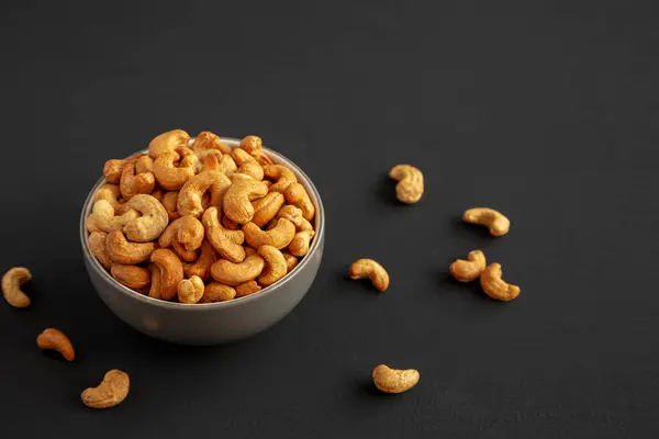 Stock image Roasted Organic Cashews in a Bowl on a black background, side view.