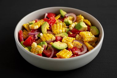 Siyah arka planda bir kasede sağlıklı taze mısır salatası, yan görüş. Yakın plan..