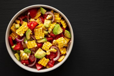 Siyah arka planda bir kasede sağlıklı taze mısır salatası, üst manzara. Dümdüz, tepeden, yukarıdan. Boşluğu kopyala.