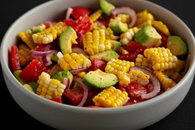 Sağlıklı Taze Mısır Salatası Siyah arka planda bir kasede, yan görünüm. 