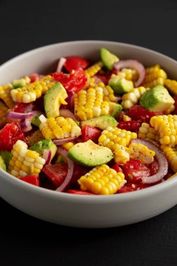 Siyah arka planda bir kasede sağlıklı taze mısır salatası, yan görüş. Yakın plan..