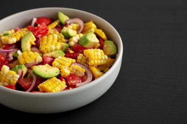 Siyah arka planda bir kasede sağlıklı taze mısır salatası, yan görüş. Metin için boşluk.