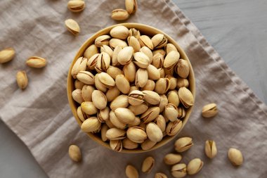 Kavrulmuş ve tuzlu şam fıstığı bir kasede gri arka planda, üst manzara.