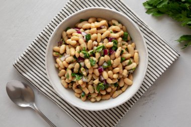 Ev yapımı beyaz fasulye salatası, sebzeli ve soğanlı, en iyi manzara. Dümdüz, tepeden, yukarıdan.