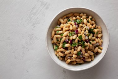 Ev yapımı beyaz fasulye salatası, sebzeli ve soğanlı, en iyi manzara. Dümdüz, tepeden, yukarıdan.