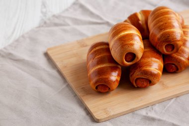 Bambu tahtasında ev yapımı sosisli çörekler, yan görüş. Boşluğu kopyala.