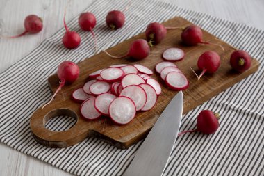 Kesme tahtasındaki ham kırmızı turp dilimleri, yan görünüm.