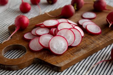 Kesme tahtasındaki ham kırmızı turp dilimleri, yan görünüm. 