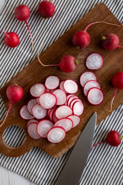 Kesme tahtasındaki ham kırmızı turp dilimleri, üst görünüm. 