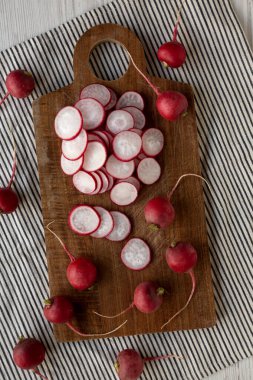 Kesme tahtasındaki ham kırmızı turp dilimleri, üst görünüm. 