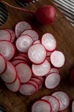 Kesme tahtasındaki çiğ kırmızı turp dilimleri. Düz uzanın, başınızın üstünde.