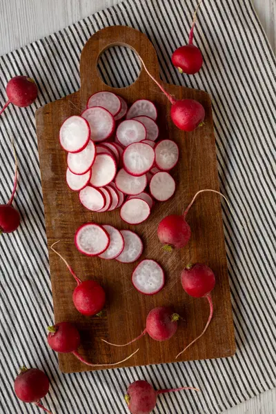 Kesme tahtasındaki ham kırmızı turp dilimleri, üst görünüm. 
