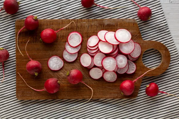 Kesme tahtasındaki ham kırmızı turp dilimleri, üst görünüm. 