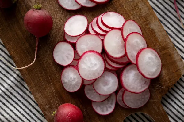 Kesme tahtasındaki çiğ kırmızı turp dilimleri. Düz uzanın, başınızın üstünde.