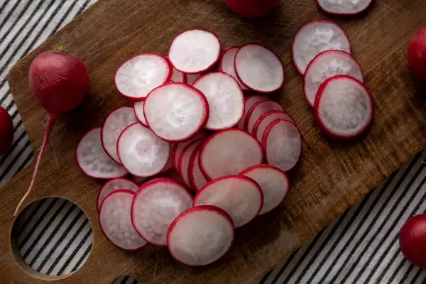 Kesme tahtasındaki çiğ kırmızı turp dilimleri. Düz uzanın, başınızın üstünde.
